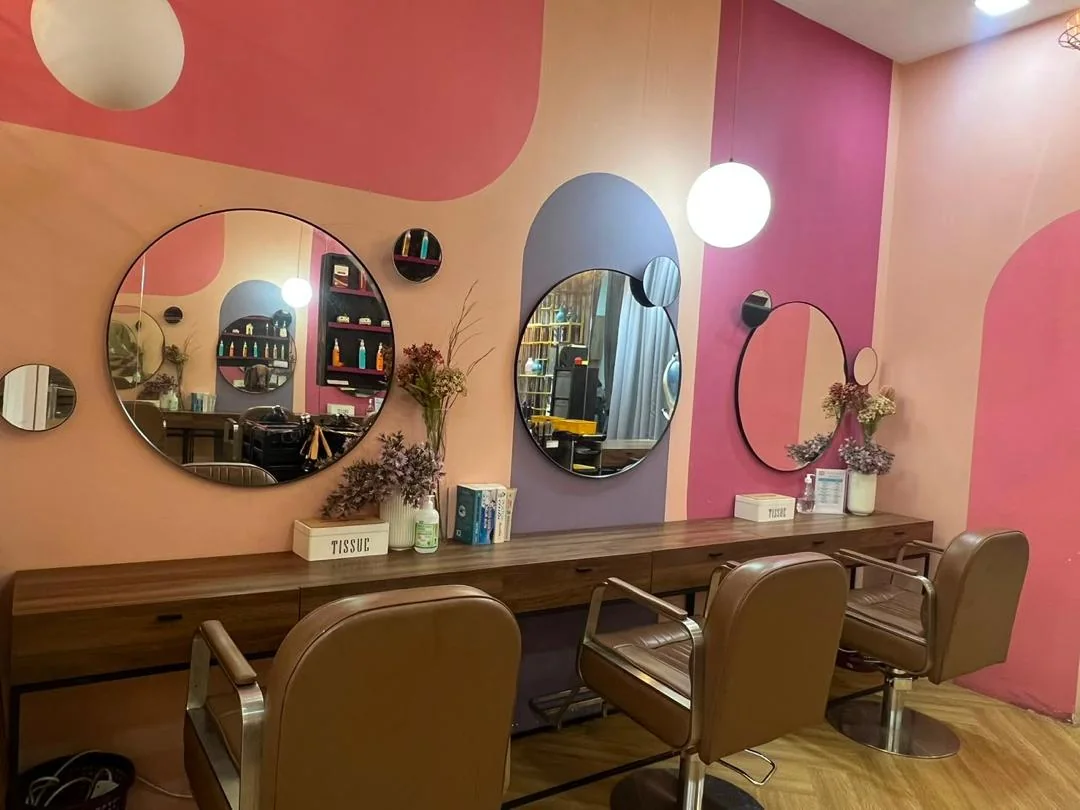 Row of styling chairs and round mirrors on pink and lilac walls at Dashing Diva Plaza Damas