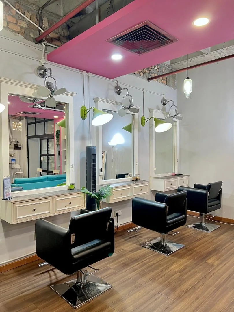 Row of black styling chairs and mirrors under a pink ceiling at Dashing Diva Shah Alam